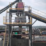 Imagine a stației de betoane, evidențiind turnul tehnic central, cu echipamente de automatizare și control integrate, utilizate pentru monitorizarea și gestionarea procesului de producție a betonului.